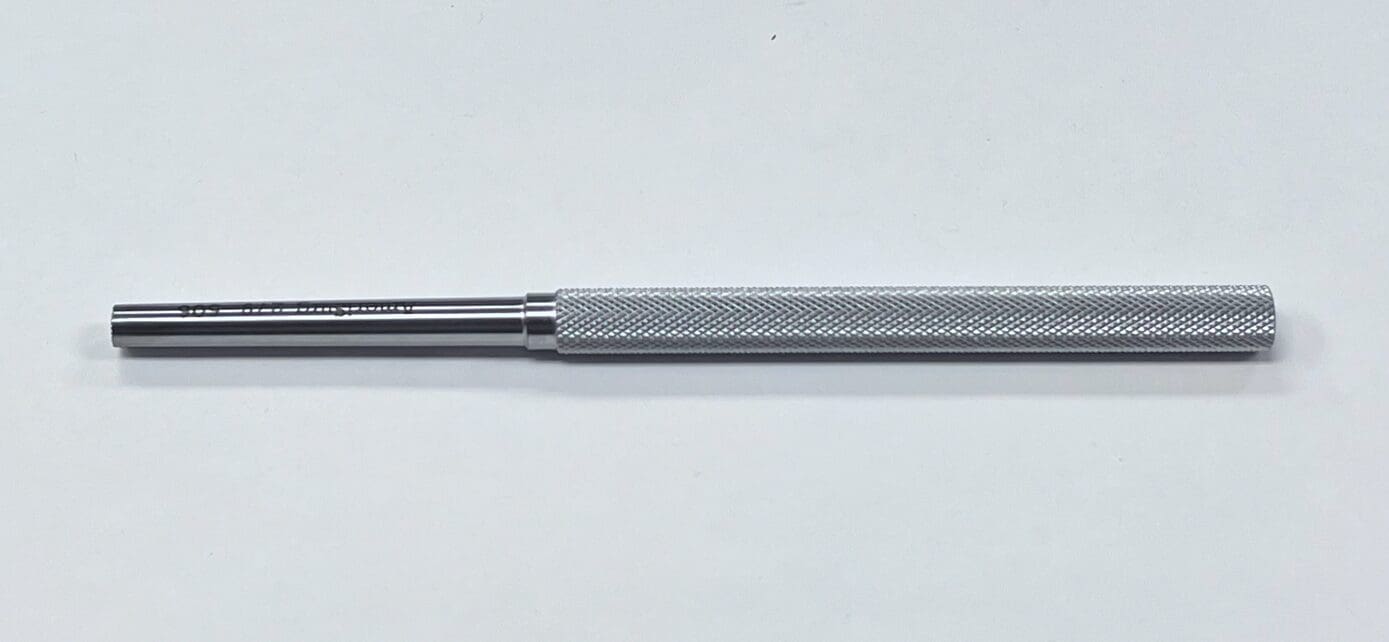 A BONE TAMP with a metal handle on a white surface.
