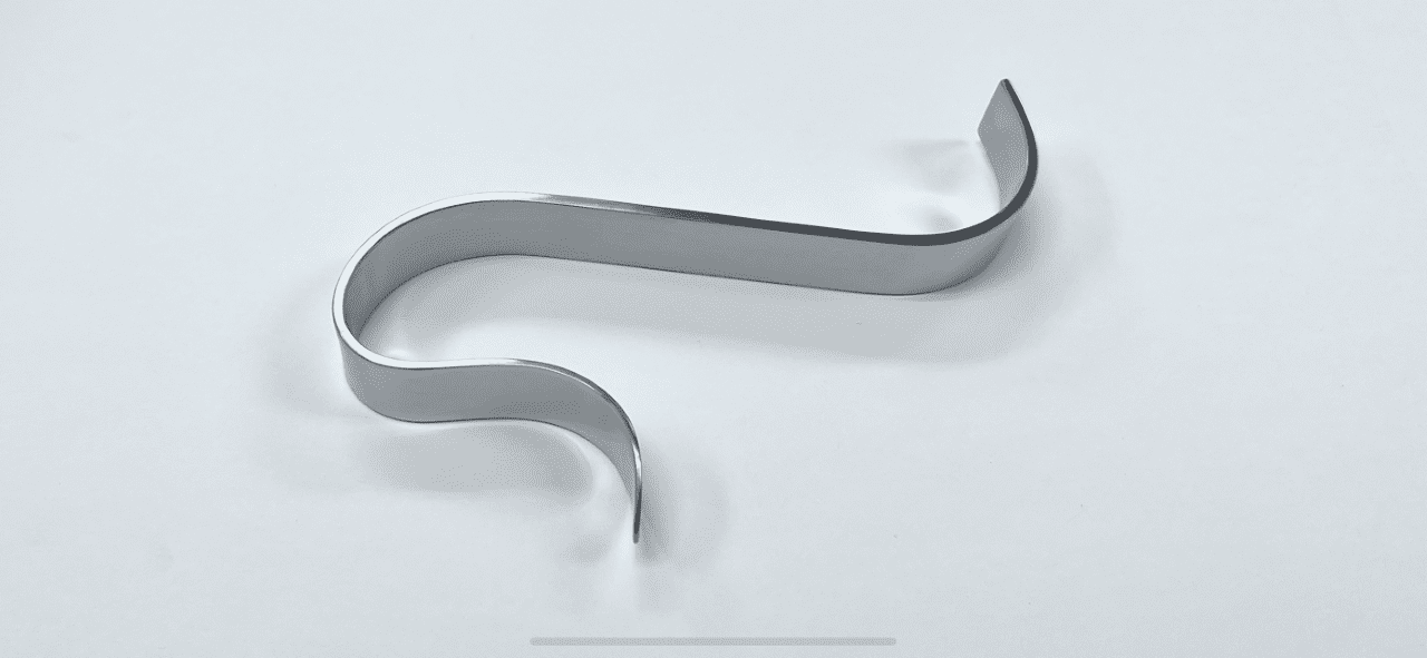A metal S TOTAL KNEE RETRACTOR on a white surface.
