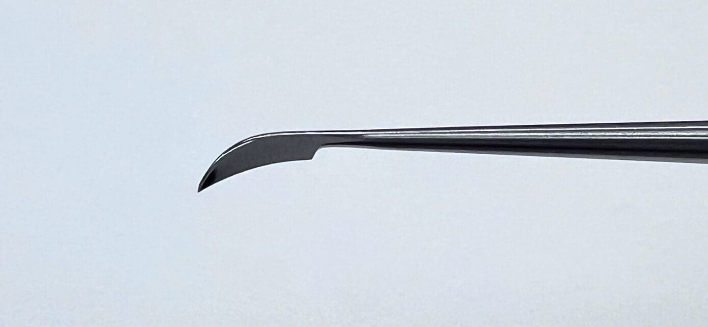 A close up of a sickle knife on a white background.