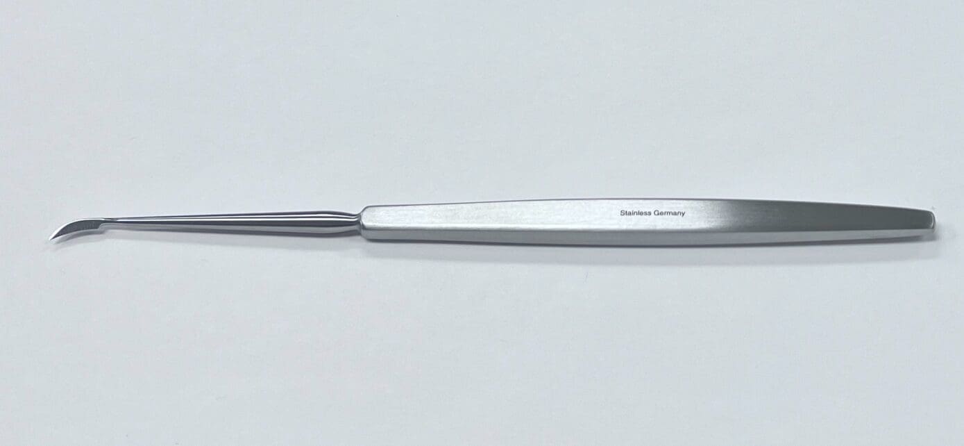 A small SICKLE KNIFE on a white surface.
