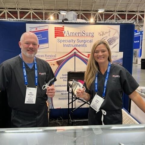 Two people standing in front of a booth at a trade show.